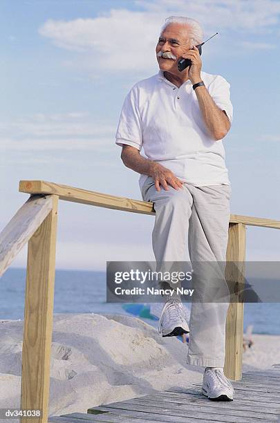 senior citizen man on cellphone at beach - citizen stockfoto's en -beelden