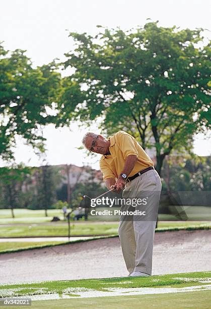 man taking swing with putter - spectacles bunkers stock pictures, royalty-free photos & images