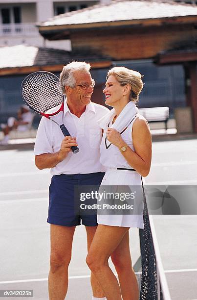 couple talking while standing on tennis court - tennis court stock pictures, royalty-free photos & images