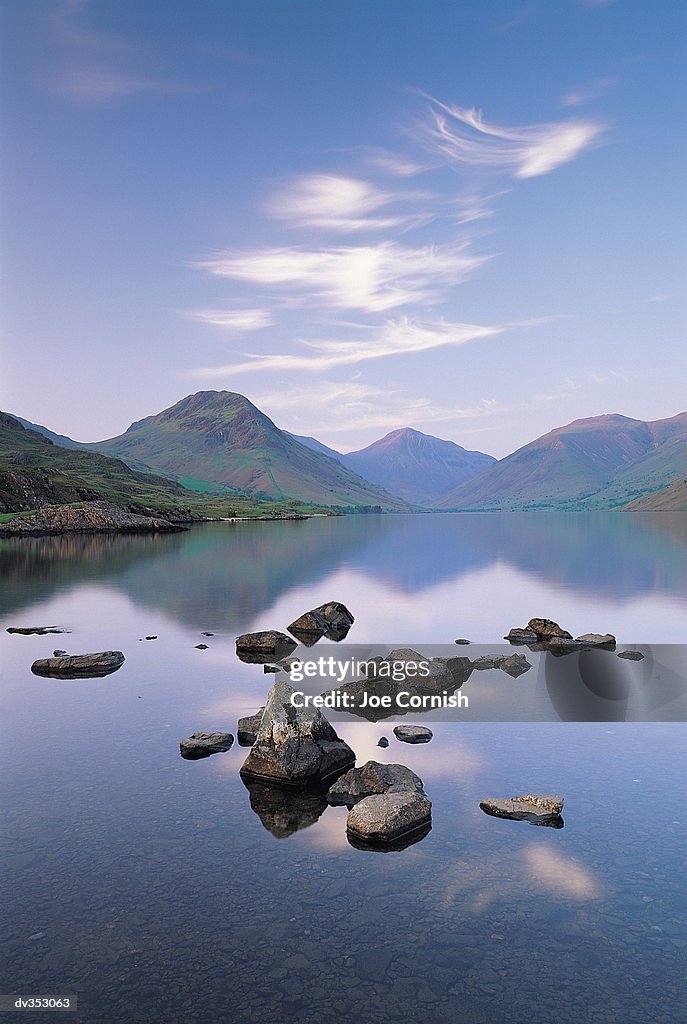 Rocks in lake surrounded by mountains