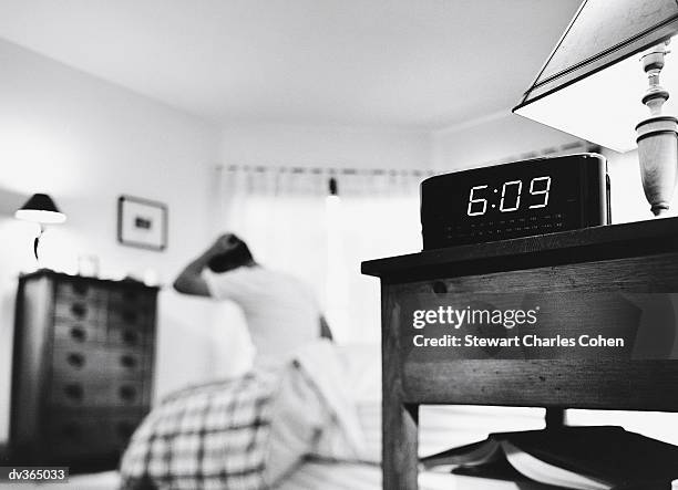 alarm clock with man getting out of bed in background - stewart stock pictures, royalty-free photos & images
