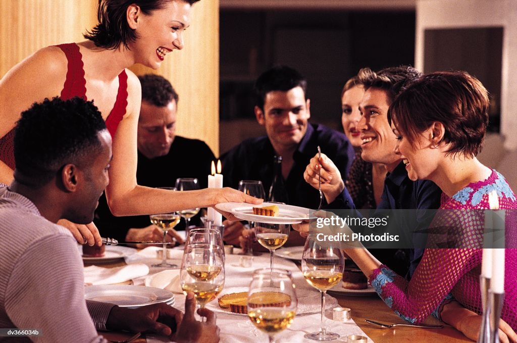 Friends chatting while hostess serves dessert