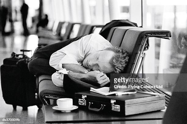 napping businessman at airport - jetlag stock-fotos und bilder