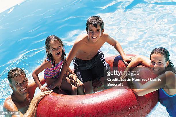 family playing with rubber ring in swimming pool - rubber ring stock-fotos und bilder