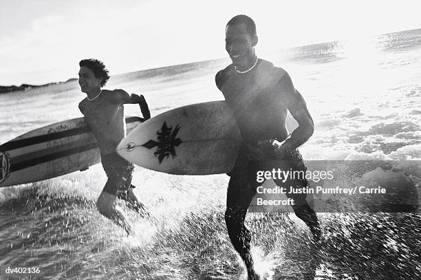 two surfers jogging out of ocean - carrie black photos et images de collection