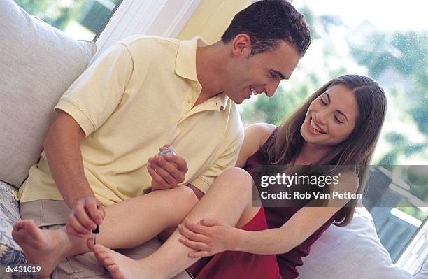 couple relaxing while husband paints wife's toe nails - toe stockfoto's en -beelden