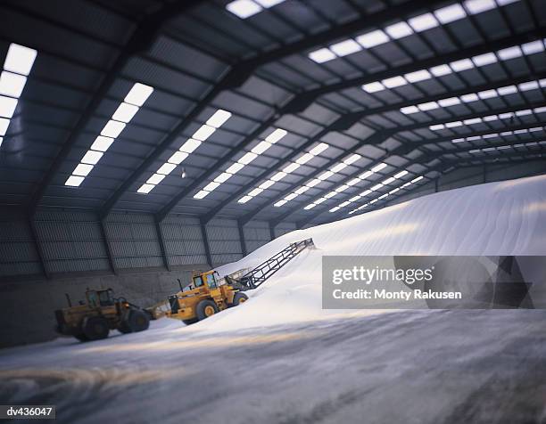 bulldozer piling mounds of sugar in warehouse - sugar stock pictures, royalty-free photos & images