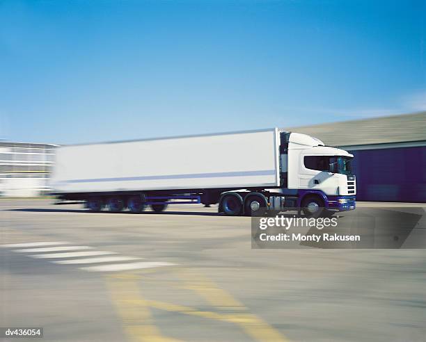 tractor trailer driving through empty lot - schwenk stock-fotos und bilder
