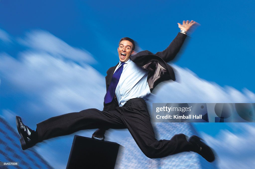 Businessman jumping in air holding briefcase