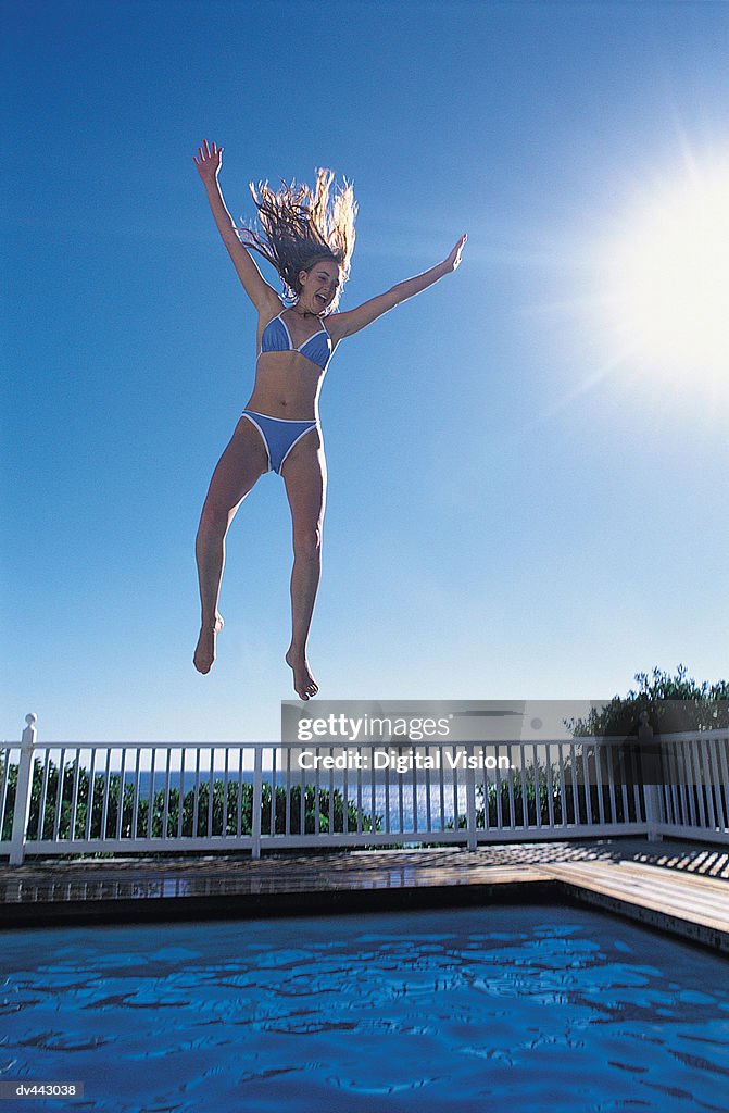 Woman jumping into a swimming pool