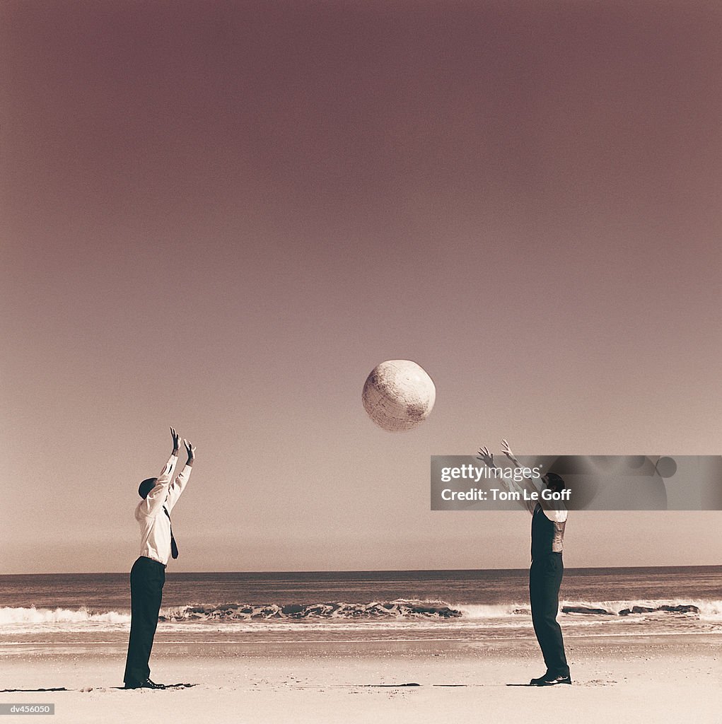 Two businessmen playing catch with globe