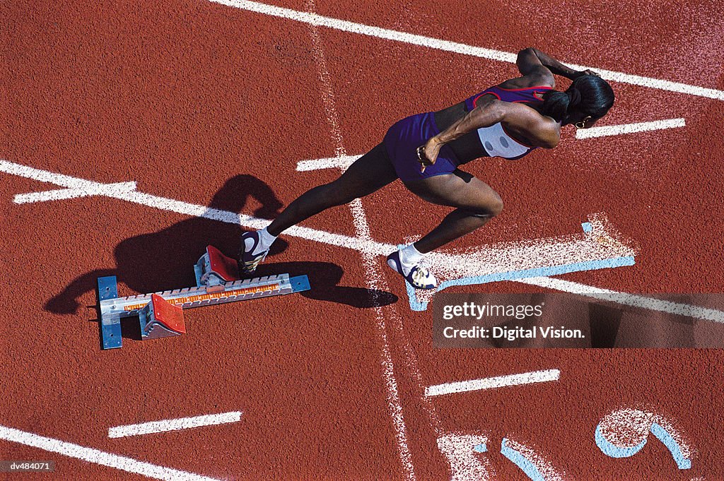 Female runner leaving starting blocks