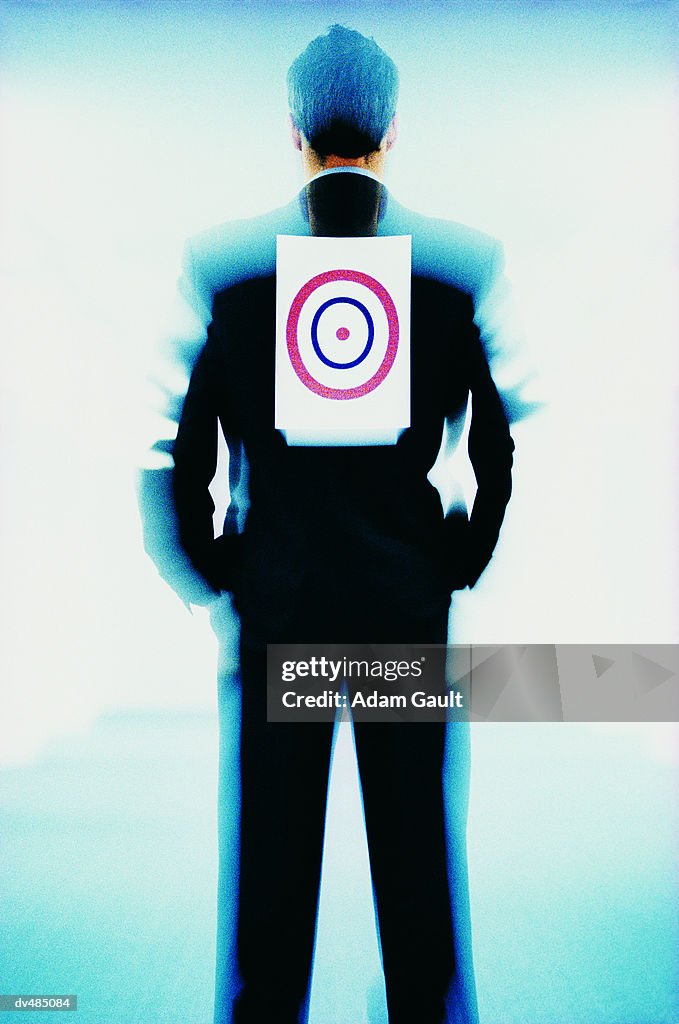 Rear View of a Businessman With His Hands in His Pockets and a Bulls Eye on His Back