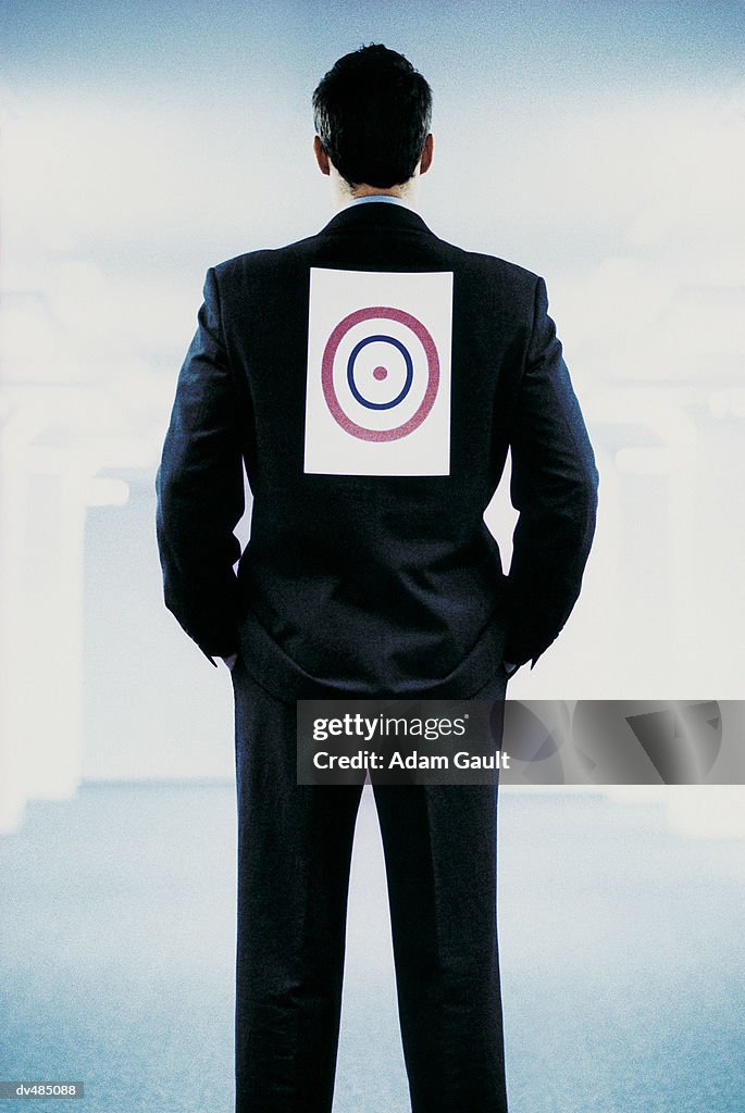 Rear View of a Businessman With His Hands in His Pockets and a Bulls Eye on His Back