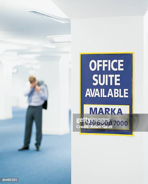 for sale sign in front of a businessman with his hand on his head in an empty open plan office - hand on head foto e immagini stock