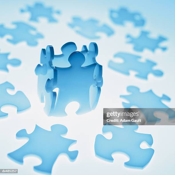 jigsaw puzzle pieces standing in a huddle among scattered shapes - beca stock-fotos und bilder