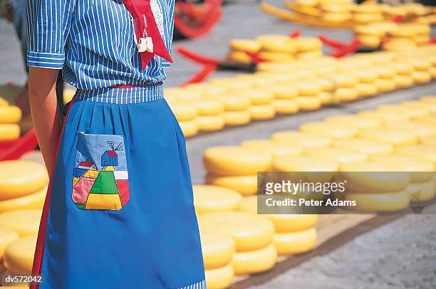 woman in uniform standing in front of rows of cheese, alkmaar, netherlands - north holland stock pictures, royalty-free photos & images