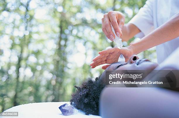 woman applying crystal therapy - crystal stock-fotos und bilder