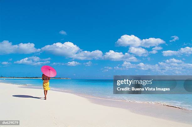 woman walking along a beach holding a parasol - buena vista stock pictures, royalty-free photos & images