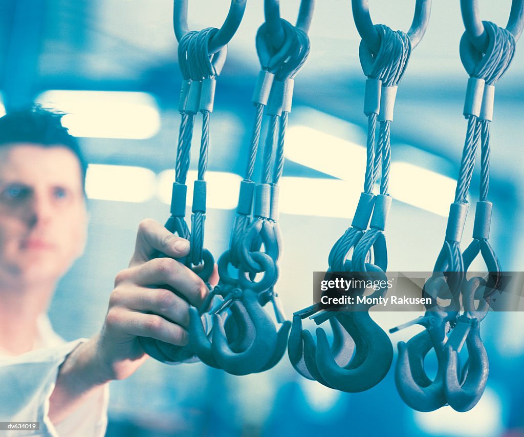 Workman holding hooks in factory