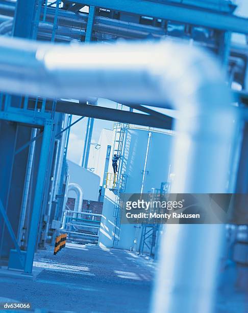 man climbing ladder in power station - monty rakusen stock-fotos und bilder