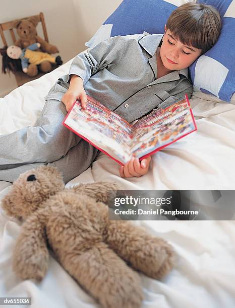 boy reading a book in bed - daniel stock pictures, royalty-free photos & images