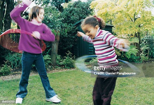 two girls playing with plastic hoops in a garden - daniel fotografías e imágenes de stock