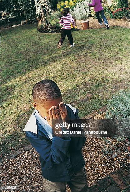 children playing hide and seek in a garden - daniel stock pictures, royalty-free photos & images