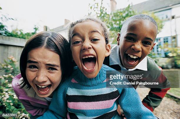 portrait of three children shouting in a garden - daniel fotografías e imágenes de stock