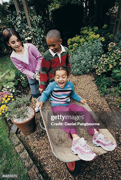 three children playing with a wheelbarrow - daniel stock pictures, royalty-free photos & images