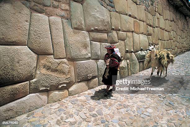 quechua woman passing inca wall, peru - quechuas fotografías e imágenes de stock