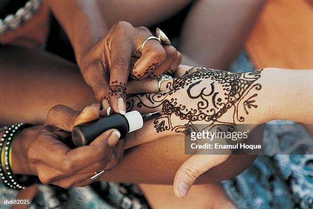 close-up of a woman having a henna tattoo on her hand - henna hands stock-fotos und bilder