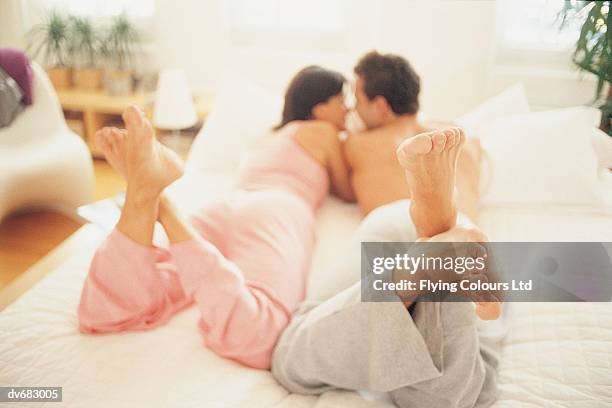 couple lying in bed - woman lying on stomach with feet up fotografías e imágenes de stock