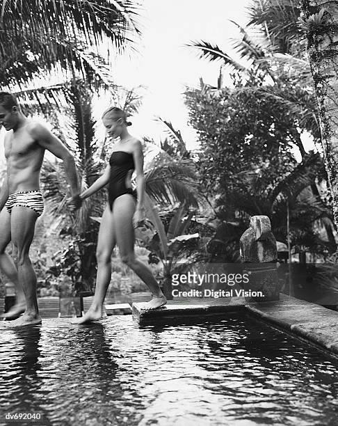 portrait of a couple walking by a swimming pool - young men in speedos stock-fotos und bilder