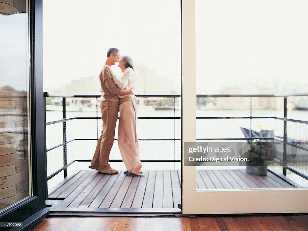 Mature Couple Embracing on the Balcony of Their Apartment