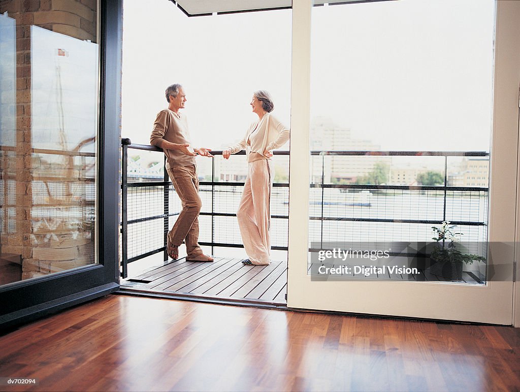 Mature Couple Talking on the Balcony of Their Apartment