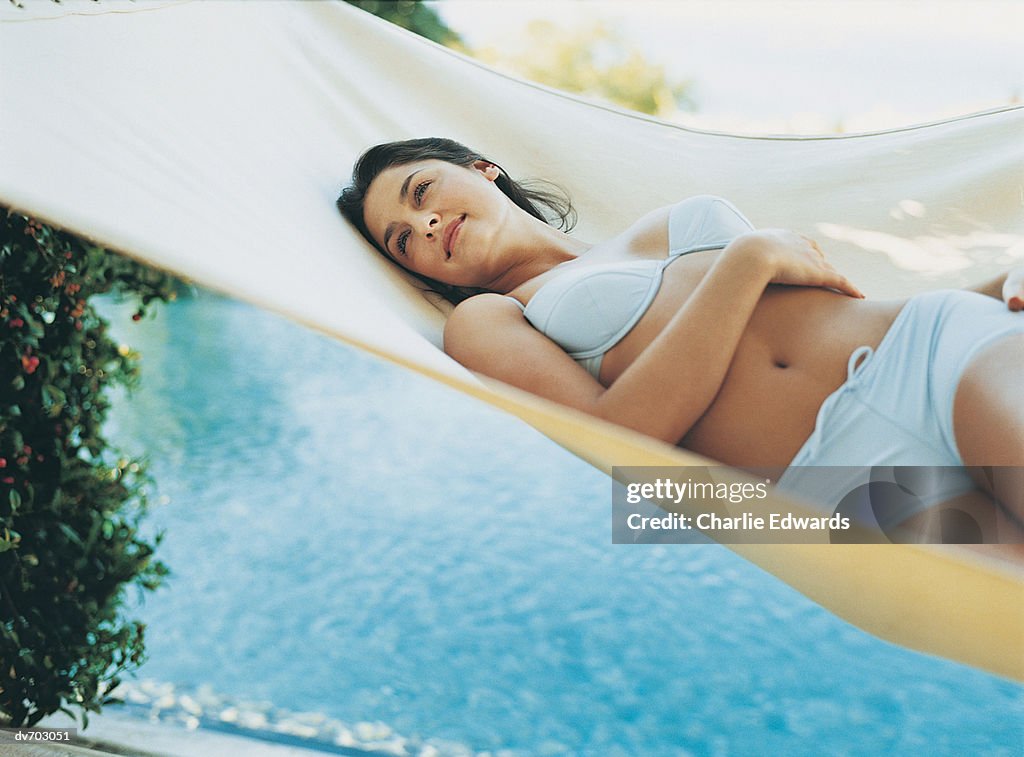 Woman Lying in a Hammock next to a Swimming Pool