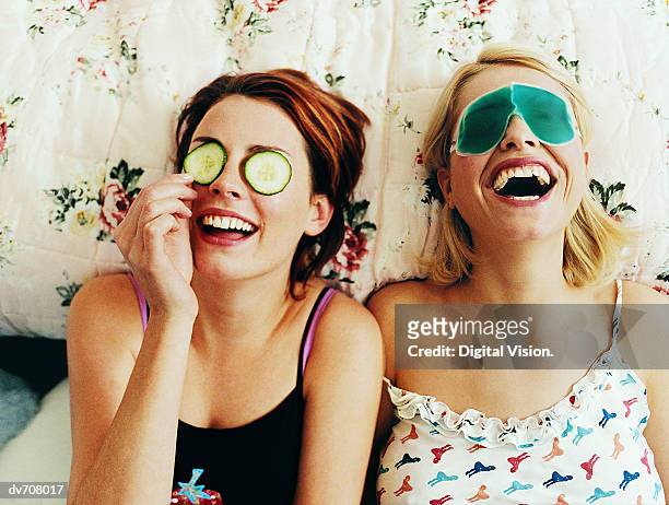 two female teenagers lying in bed wearing eye masks - positive emotion stock-fotos und bilder