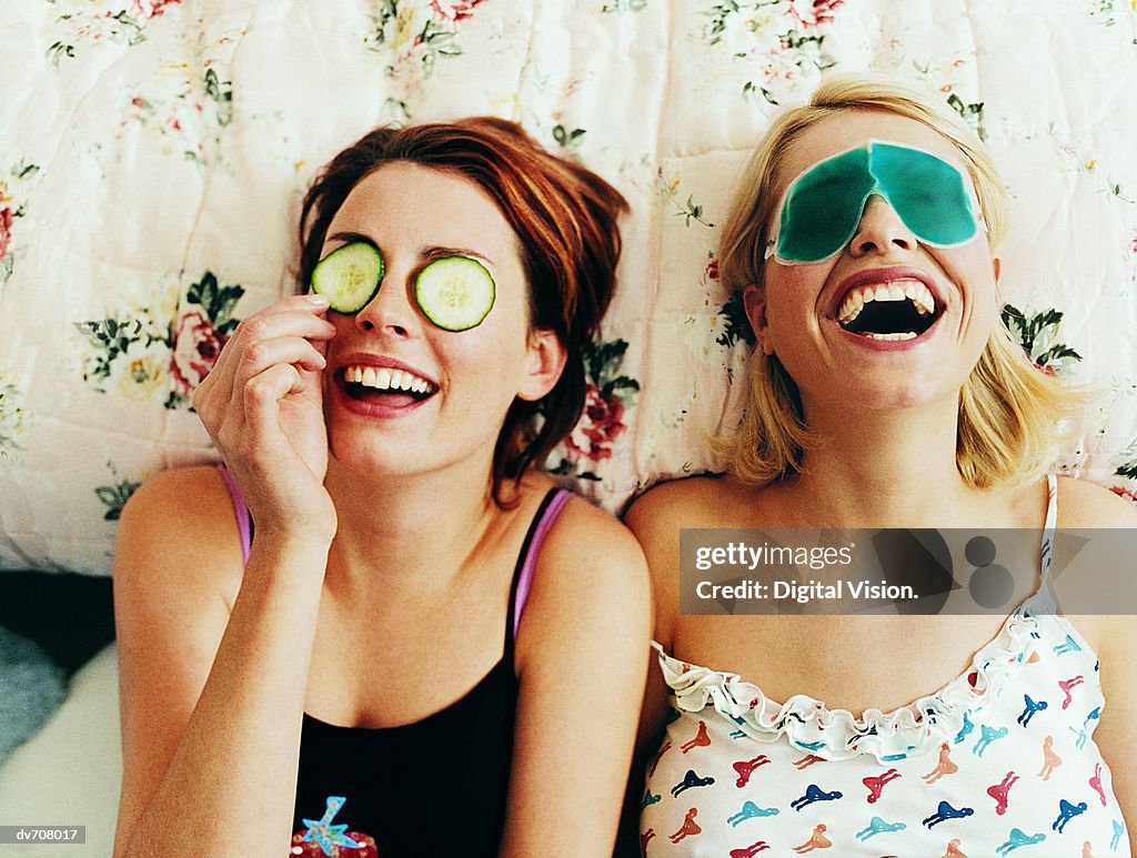 Two Female Teenagers Lying in Bed Wearing Eye Masks