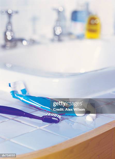 toothbrush and toothpaste by a sink - toothpaste tube stock pictures, royalty-free photos & images
