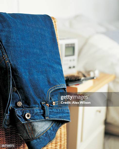 pair of jeans in a laundry basket with a bed in the background - wilson stock-fotos und bilder