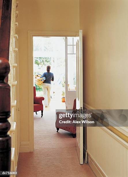 view down a corridor of a woman carrying a basket of laundry - wilson stock-fotos und bilder