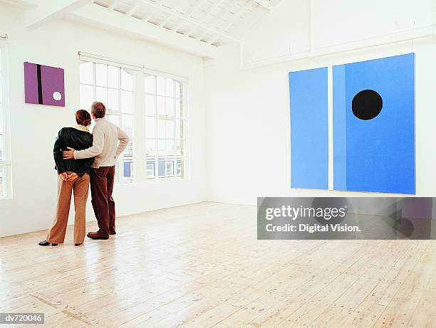 couple looking at a painting in an art gallery - modern art photos et images de collection