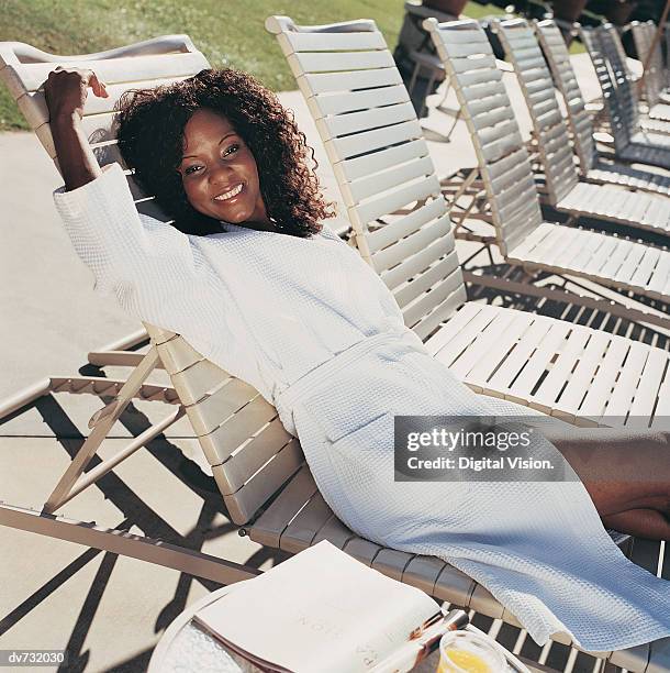 portrait of a woman in a dressing gown stretching on a sun lounger - dressing up ストックフォトと画像
