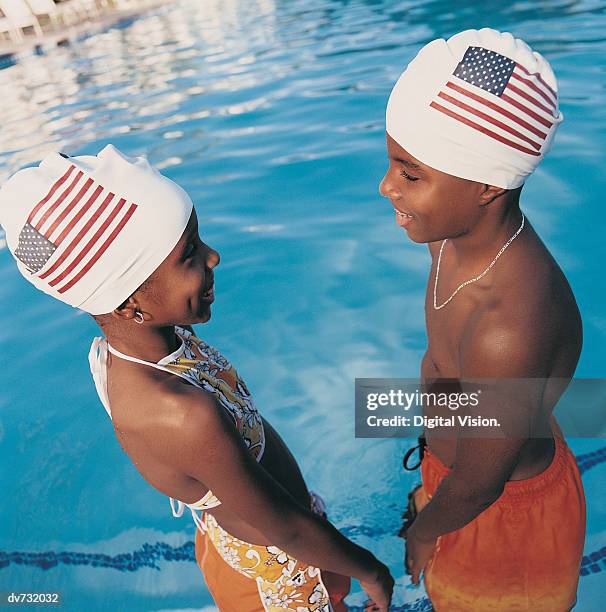 two teenagers face to face standing in a swimming pool wearing stars and stripes swimming caps - lionsgate uk screening of film stars dont die in liverpool after party stockfoto's en -beelden