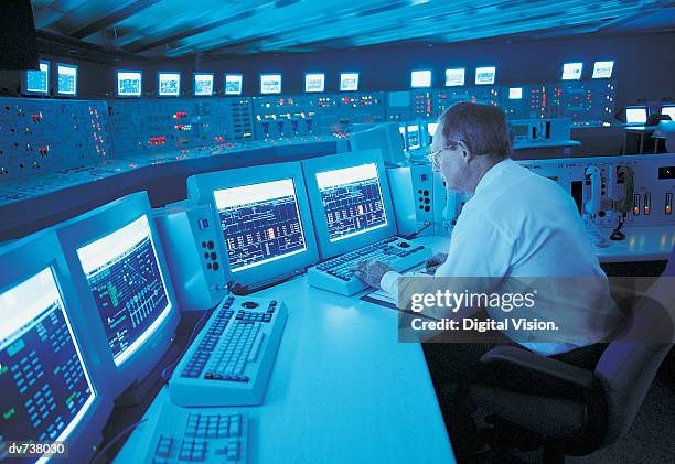 engineer sitting at control panel of nuclear power station - control room stock pictures, royalty-free photos & images