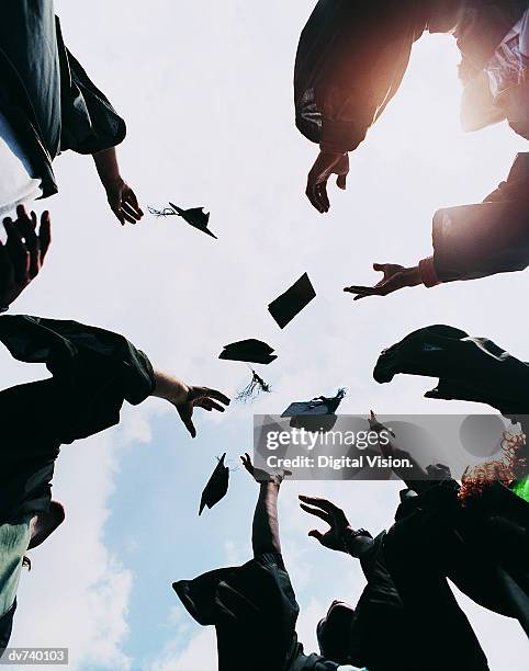 five students throwing their mortar boards in the air at graduation - mortar board stock pictures, royalty-free photos & images