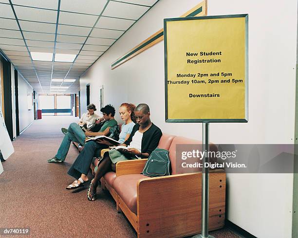 four students waiting in a corridor - anmelden stock-fotos und bilder