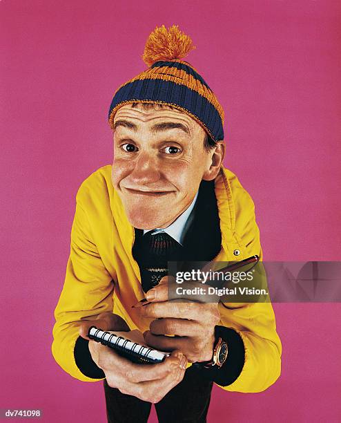 portrait of a geeky man holding a notepad and pencil - bobble hat stock pictures, royalty-free photos & images