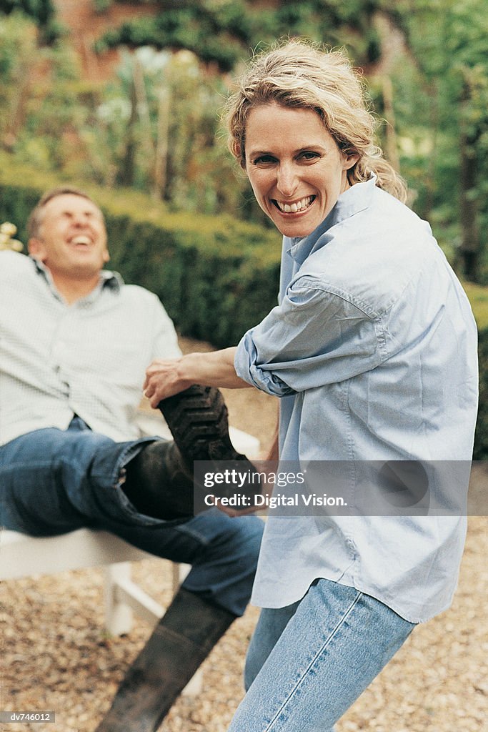 Portrait of a Woman Struggling to Pull a Man's Wellington Boot